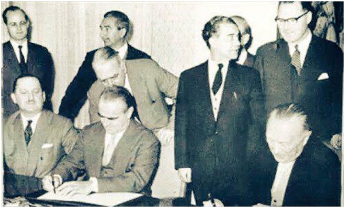 وزیر اقتصاد یونان در کنفرانس لندن در 1953 درحال امضای توافقنامهای که بر آن اساس 50 درصد بدهی آلمان بخشوده شد.