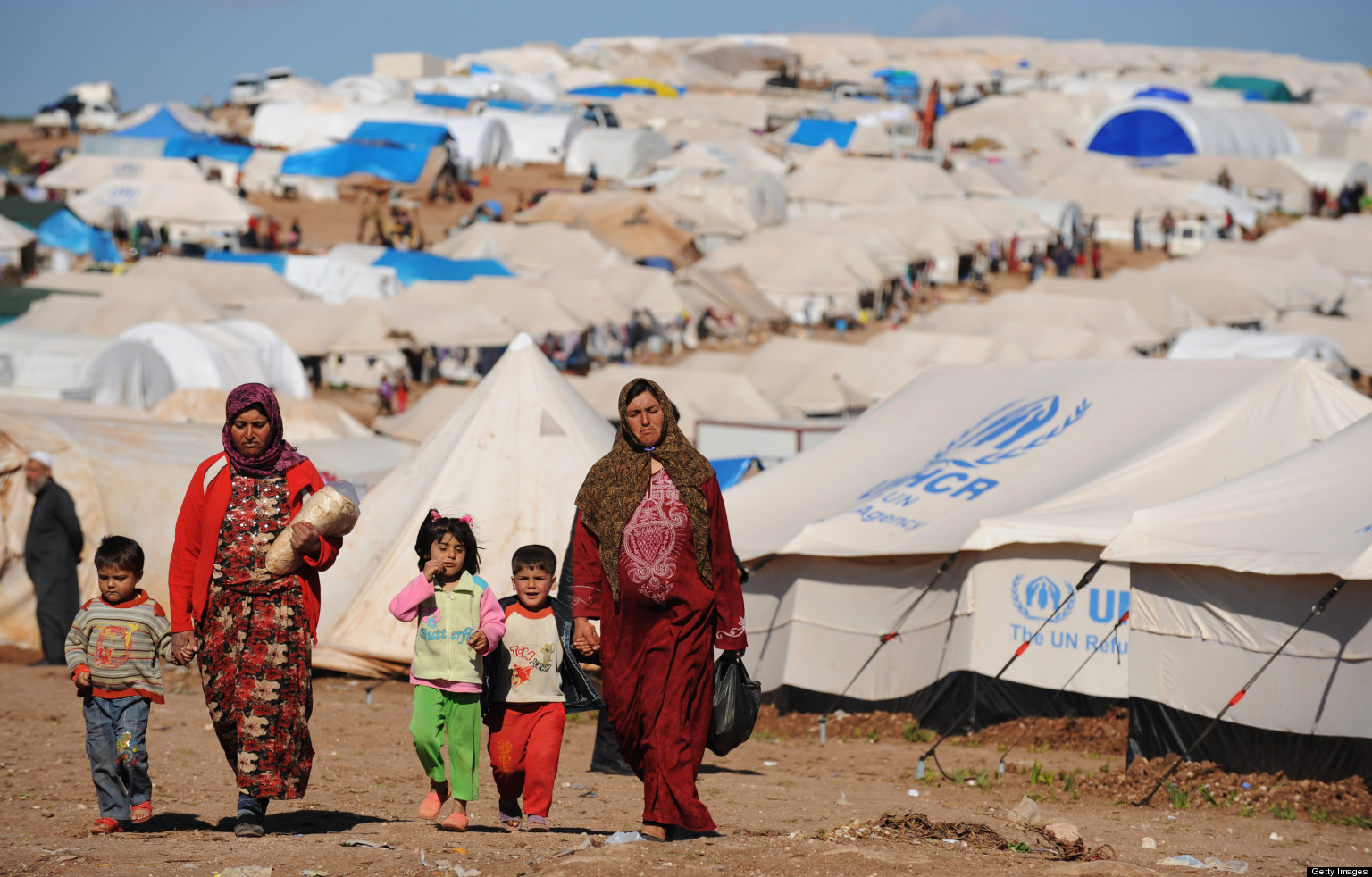 Syrian internally displaced people walk in the Atme camp, along the Turkish border in the northwestern Syrian province of Idlib, on March 19, 2013. The conflict in Syria between rebel forces and pro-government troops has killed at least 70,000 people, and forced more than one million Syrians to seek refuge abroad. AFP PHOTO/BULENT KILIC        (Photo credit should read BULENT KILIC/AFP/Getty Images)